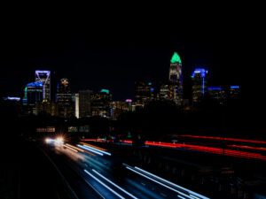 City skyline at night with light trails from moving vehicles.