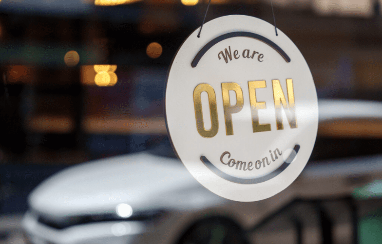 A glass door sign saying 'We are OPEN, Come on in!'