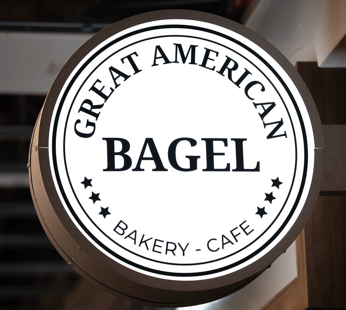 Illuminated round bakery sign reading "BAGEL"