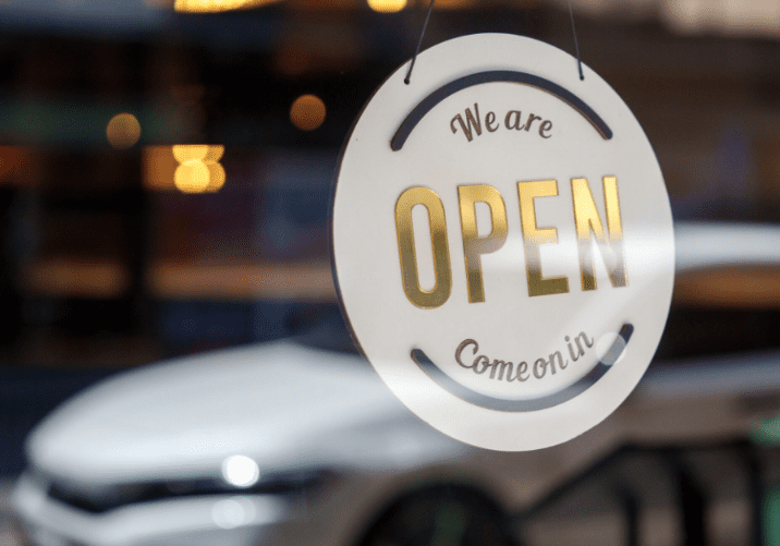 A glass door sign saying 'We are OPEN, Come on in!'